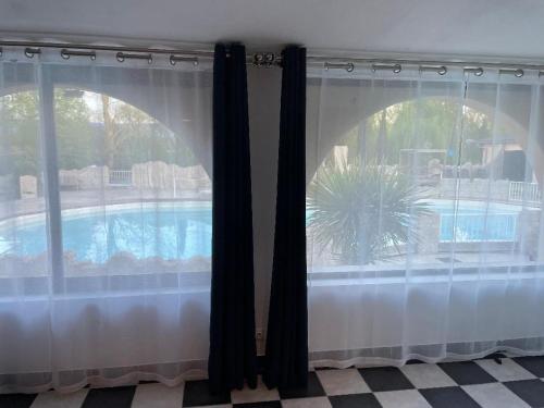 a view of a pool from a window with curtains at gîtes Studio de tourisme du Domaine Piscine Spa Balnéo in Lescout