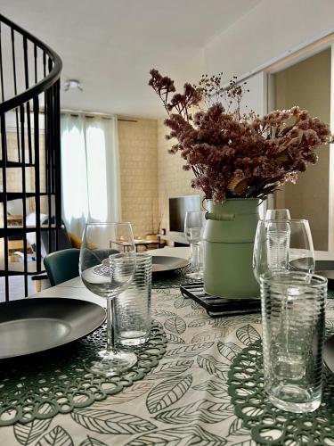 une table avec des verres et un vase avec des fleurs. dans l'établissement Jolie maison de village proche de la mer, à Sainte-Marie-la-Mer