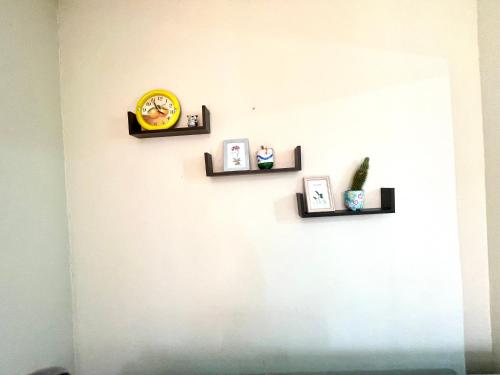 a wall with three shelves and a clock on it at Oasis de Paz 1.2 in Jarabacoa