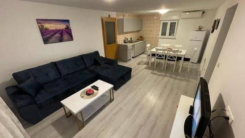 Il comprend un salon avec un canapé bleu et une cuisine. dans l'établissement Apartmani Danica, à Orebić