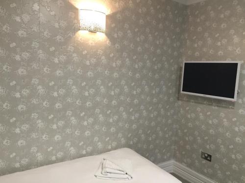 - une chambre avec un lit et une télévision murale dans l'établissement Paddington Apartments, à Londres