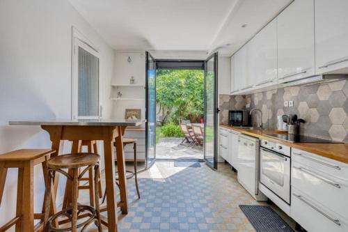 une cuisine avec des placards blancs, une table et des tabourets dans l'établissement Maison au calme à 10 minutes à pied du métro ligne 11, à Romainville