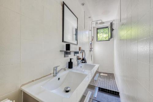 une salle de bain blanche avec un lavabo et un miroir dans l'établissement Maison au calme à 10 minutes à pied du métro ligne 11, à Romainville