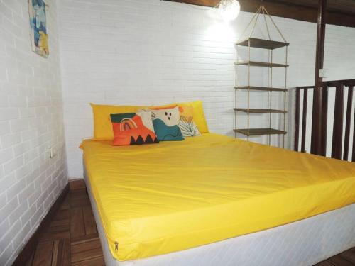 ein gelbes Bett mit bunten Kissen in einem Zimmer in der Unterkunft Praia Guaratuba Costa do Sol - 600mt da praia in Bertioga