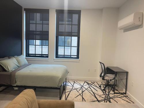 a bedroom with a bed and a couch and windows at Hartford Downtown: 2mins walk to XL Center in Hartford