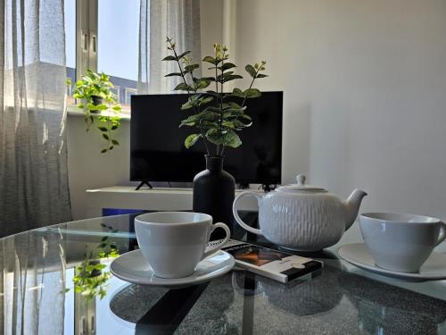 a glass table with two cups and a vase on it at Spacious Two Bedroom Apartment with 2 En-suite Bathrooms in Northampton