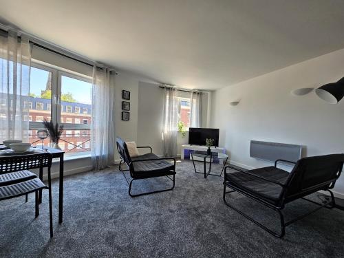 a living room with chairs and a table and a television at Spacious Two Bedroom Apartment with 2 En-suite Bathrooms in Northampton