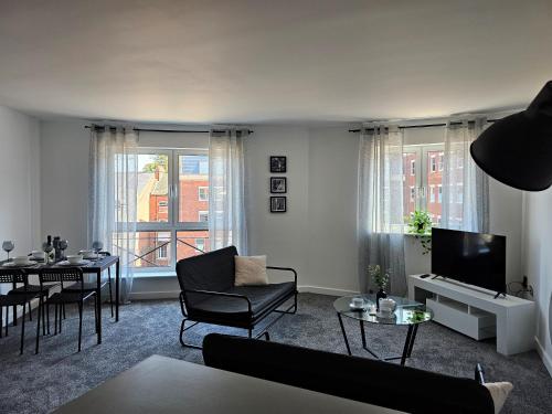 a living room with a couch and chairs and a tv at Spacious Two Bedroom Apartment with 2 En-suite Bathrooms in Northampton