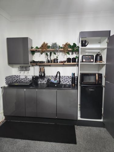 a kitchen with a sink and a refrigerator at Quantock Lodge Vicarage 2 in Rochester