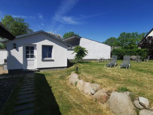 a white house with chairs in the yard at Reetferienhaus - Schaprode Hafen in Schaprode