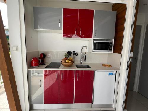 a kitchen with red and white cabinets and a sink at LE DOUX PARADISE in Sainte-Rose