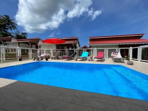 a large blue swimming pool in front of a house at LE DOUX PARADISE in Sainte-Rose