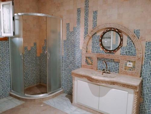 a bathroom with a shower and a sink and a mirror at Dar Soltana in Sidi Daoud