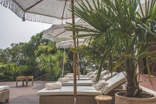a patio with a bunch of chairs and an umbrella at Villa Pietra Estoril Eco Guesthouse in Estoril
