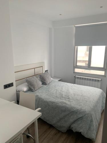 a white bedroom with a bed and a desk at Apartamento turístico A Coruña in A Coruña