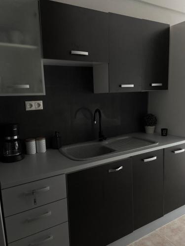 a kitchen with black cabinets and a sink at Souzana Suite Leptokarya in Leptokarya