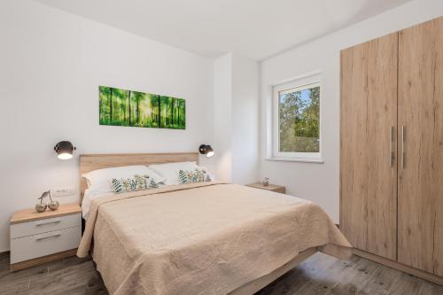 a white bedroom with a large bed and a window at Apartmants Belvedere Rijeka in Rijeka