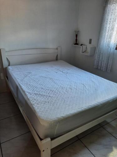 een bed in een slaapkamer met een wit matras bij Casa de praia in Passo de Torres