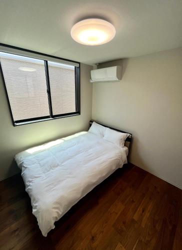 a small bedroom with a white bed and two windows at Flower Base Fuji in Muromimachi