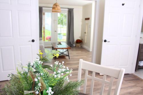 a living room with two white chairs and a table with flowers at Gateway to Greenwich Suites in Saint Peters