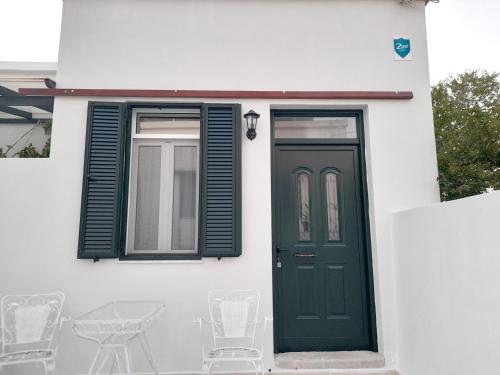 a white house with a green door and windows at Ζoe Studios in Kýthira