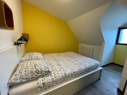 Cama en habitación con pared amarilla en Villa Marylou, en Bernières-sur-Mer