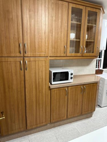 eine Küche mit Holzschränken und einer Mikrowelle auf der Theke in der Unterkunft Apartamento Vista-Beach in Cádiz
