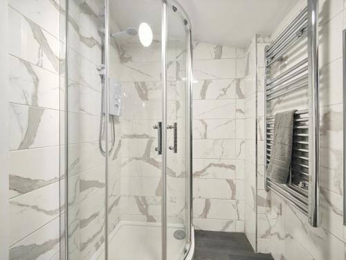 een douche in een badkamer met witte marmeren muren bij Cosy Holiday Home in Hazel Grove - Self Catering Apartment 1 in Hazel Grove