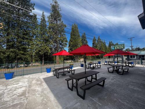 un grupo de mesas de picnic con sombrillas rojas en A1 Choice Inn, en Mount Shasta