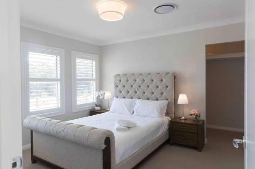 a bedroom with a large white bed with a tufted headboard at WineCountry Holiday House in Branxton