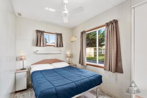 a bedroom with a blue bed and a window at Victor Harbor Holiday Park in Victor Harbor