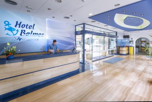 a man standing at the counter of a hotel and ballinas hotel room at GHT Balmes, Hotel-Aparthotel&SPLASH in Calella