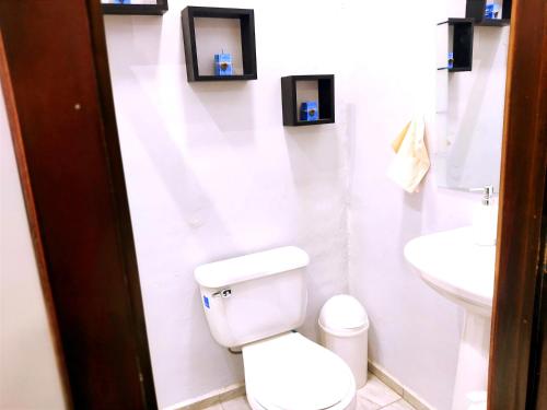 een witte badkamer met een toilet en een wastafel bij Mini Suite totalmente amoblado recién reconstruido, camas muebles, bajilla, electrodomésticos totalmente nuevos Suit muy espaciosa, ideal para parejas o personas solas que viajan de trabajo in Cuenca