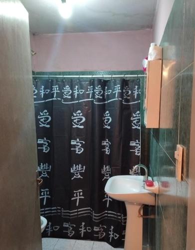 a bathroom with a black shower curtain and a sink at Doña Chicha in Tinogasta