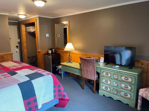a bedroom with a bed and a desk with a television at Northern Lights Lodge in Stowe