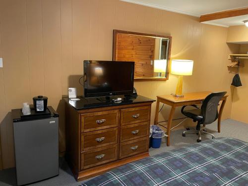 a hotel room with a television on a dresser with a desk at Northern Lights Lodge in Stowe