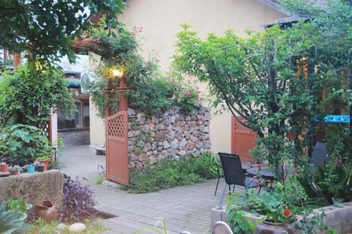a patio with a stone wall and a chair in a garden at 张家界天门山伴田居民宿 in Zhangjiajie
