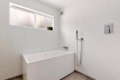 a white bathroom with a sink and a window at Piccolo House in Hakuba