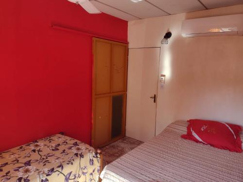 1 dormitorio con cama y pared roja en Casa Merceditas en Posadas