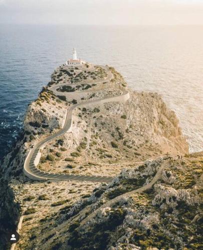 a road leading to a lighthouse on an island in the ocean at Summer in ALCUDIA with Pool-A/C-WIFI-Netflix... in Port d'Alcudia