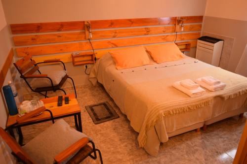 a bedroom with a large bed and a chair at hosteria las cachi alojamiento in Esquel