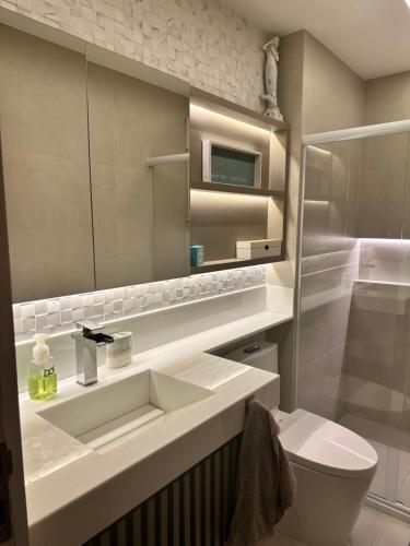 a bathroom with a sink and a toilet and a mirror at Cobertura Duplex Beira Mar Praia do Morro, Guarapari in Guarapari