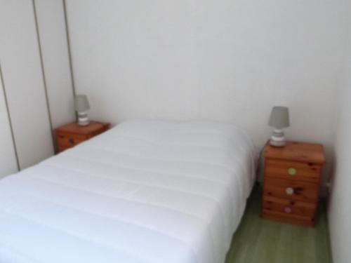 - une chambre avec un lit blanc et 2 tables de chevet dans l'établissement Charmante maisonnette avec jardinet à 650m de la plage, au cœur d'une copropriété calme - FR-1-194-269, à La Tranche-sur-Mer