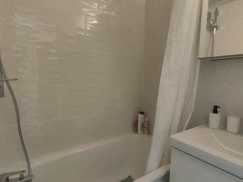 une salle de bain blanche avec une baignoire et un lavabo dans l'établissement Duplex 2 pièces près des télécabines avec parking, idéal pour 4 personnes - FR-1-234-307, à Cauterets