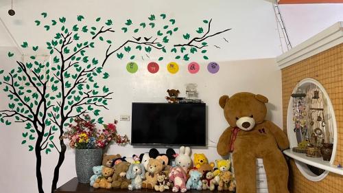 a room with a tv and a teddy bear and stuffed animals at Feng Ge Yuan Homestay in Dongshan