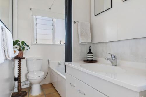 a white bathroom with a toilet and a sink at Home on The Grange in Mt Eden in Auckland