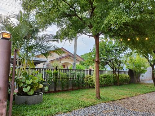 a house with a fence and a tree in a yard at Walai House วลัยเฮ้าส์ กาญจนบุรี in Ban Tha Nam Tun