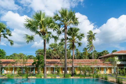 eine Villa mit Palmen und einem Pool in der Unterkunft Palmera Eco Resorts Nilaveli in Trincomalee