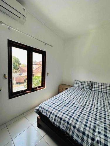 a bedroom with a bed with a plaid blanket and a window at Cc homestay dekat Malioboro in Kejayan