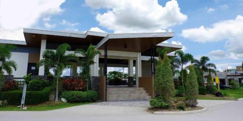 a building with a porch with palm trees and bushes at Rimaven Homes Clark-Dau (w/ Parking, Netflix, Wi-Fi) 